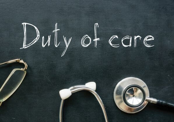 Duty of care written on a blackboard with medical instruments around it