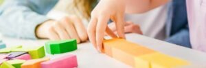 A child and a parent constructing figures out of small wooden pieces